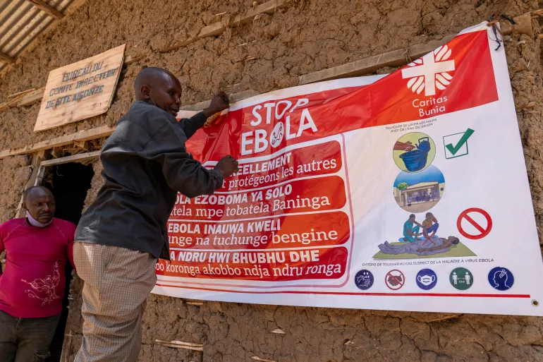 A man hangs an Ebola awareness banner in the Kigonze camp in Bunia, in the eastern Democratic Republic of the Congo